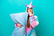© luismolinero - Young caucasian girl with unicorn pajamas holding pillow isolated on blue background happy and smiling covering mouth with hand