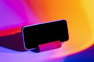 Wall Mural - mockup smartphone on phone stand on abstract background in neon gradient. mobile phone ith blank whi