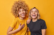 © wayhome.studio  - Best female friends laugh happily feel amused smile broadly have fun together dressed in casual t shirts isolated over vivid yellow studio background. Positive human emotions and feelings concept