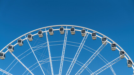 Close-up details of ferris wheel on clear blue sky background, with metal beam guides and passenger booths. Marina Mall ferris wheel, Abu Dhabi, United Arab Emirates