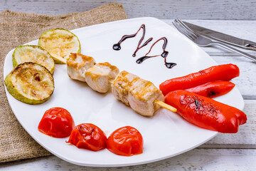 Sticker - chicken kebab with grilled vegetables on a white plate