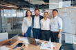 © Yaroslav Astakhov - Happy diverse professional business team stand in office near board looking at camera, smiling.