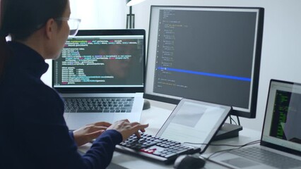 Wall Mural - Young Asian woman, developer programmer, software engineer, IT support, wearing glasses working on computer to check coding in bugging system. Back view