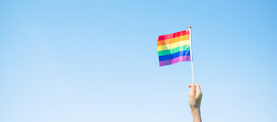 hands showing LGBTQ Rainbow flag on nature background. Support Lesbian, Gay, Bisexual, Transgender and Queer community and Pride month concept