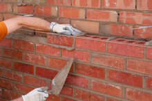 Bricklayer Laying Bricks On Mortar On New Residential House Construction. Another Brick In The Wall