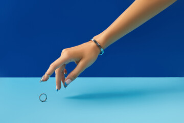 Wall Mural - Beautiful manicured womans hand with ring on blue background