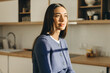 © shurkin_son - Profile picture of sun drenched beautiful female face against kitchen background, looking aside, wearing blue wool cardigan with buttons, having sensual pouty lips and long smooth hair