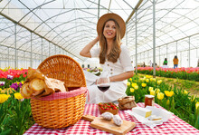 Attractive Smiling Woman Enjoying Picnic Between Tulips On Spring Time. Selective Focus.