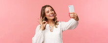 Close-up Of Satisfied Good-looking Blond Girl In White Dress, Taking Selfie, Record Mobile Phone Video, Show Okay Satisfactory Sign With Pleased Nod, Smiling Agree Or Recommend, Pink Background