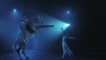 A Girl In A White Dress Rears Up A Horse With A Rider Under Beautiful Lighting, A Circus Performance. Slow Motion
