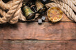 Whiskey in the drinking glass, binoculars and mooring rope on the brown wooden flat lay table background with copy space.