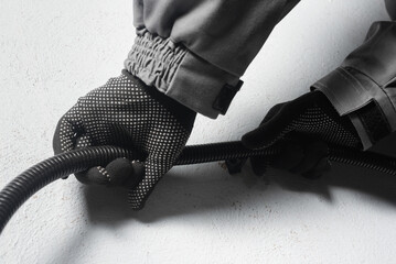 Worker is laying a corrugated pipe for laying cable on the wall close up.