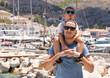 © Marina - Father and son on the background of the port in the Greek city. The boy sits on dad's shoulders.