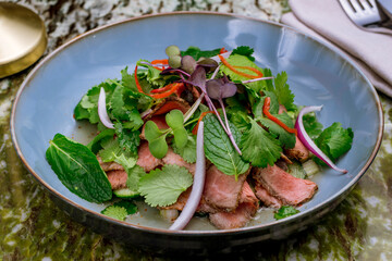 Wall Mural - Steak salad with beef and vegetables on grey plate on green marble table