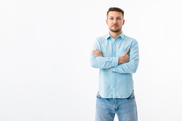 portrait of a cheerful young man in a blue shirt on a white background. the guy stands, looks at the