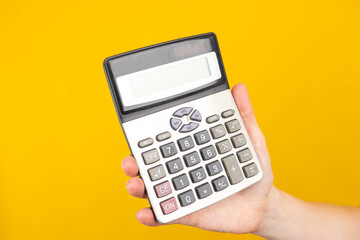 Poster - Calculator close-up. A hand with a calculator. Calculations, budgeting. Calculator as a symbol of financial calculations. Lending, calculation of the loan cost. Orange background with place for text.