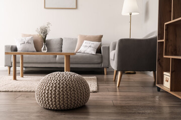 Poster - Comfortable pouf on wooden floor in living room