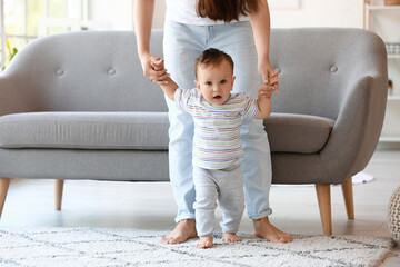 Sticker - Little baby boy learning to walk with his mother's help at home