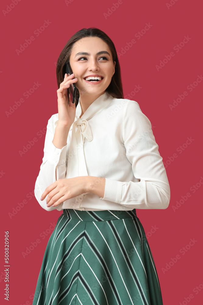Happy young woman talking by phone on color background