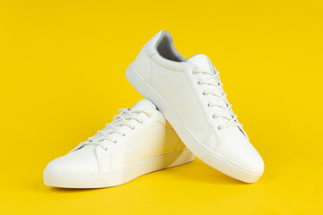 Wall Mural - Pair of new white sneakers on yellow background