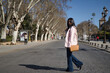 © Manuel - Young beautiful South American woman in a pink jacket, jeans, brown handbag and sunglasses, on vacation in Europe, crossing a city street. Concept vacation, travel, beauty, fashion.