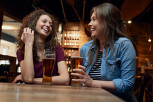 Two Happy Female Friends Having Beer And Socializing In A Pub
