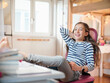 © Westend61 - Happy girl with book sitting on chair at home
