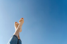 Woman With Crossed Barefeet Under Clear Blue Sky