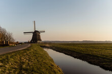 Canal By Windmill On Agricultural Field