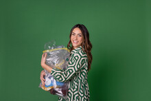 Happy Young Woman Holding Bag Of Plastic Waste Against Green Background
