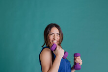Cheerful Woman With Purple Dumbbells Standing Against Blue Background