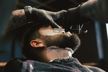 Wall Mural - Professional hairdresser working with bearded client in barbershop, closeup