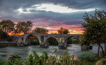 Historic Bridge Of Arta Over Arachthos River On Sunset
