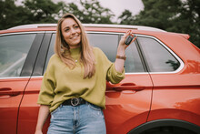 Smiling Young Woman With Key Standing In Front Of Car