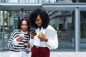 Smiling colleagues using smart phones at office park