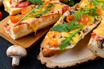 Wall Mural - Homemade pizza cooked on a baguette, Italian sandwich, close-up, dark table.