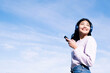 © Westend61 - Smiling woman with headphones and smart phone on sunny day