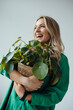 © Westend61 - Cheerful woman holding houseplant against white background