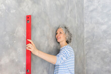 Smiling Woman With Level Measuring Tool By Gray Wall