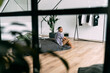 © Westend61 - Young man sitting on bed seen through glass at home