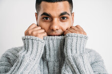Man Covering Face With Gray Woolen Sweater Against White Background