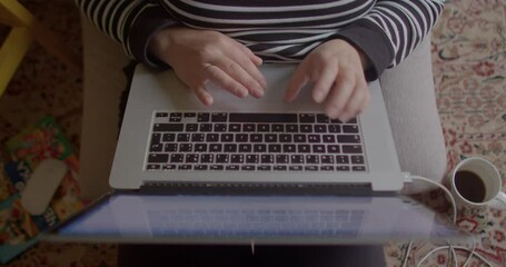 Poster - Hands use laptop keyboard while sitting at home. Application control using buttons and mouse. A glass of coffee on the floor.