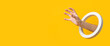 Hand with a round hole picks up an invisible object on a yellow background. Banner.