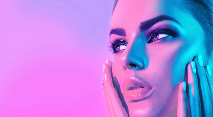Wall Mural - High Fashion model girl face in colorful bright UV lights in studio, portrait of beautiful woman with trendy make-up and manicure. Art design, colorful make up. Over colourful purple, blue background