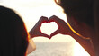 © Kiattisak - Happy young couple in love making heart shape with fingers on the beach sunset, romantic relationships in vacation holidays, enjoying with travel and resting on summer vacation or holiday concept.