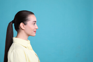 Profile portrait of young woman on light blue background. Space for text