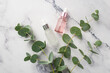 Natural cosmetics concept. Top view photo of pink and white transparent glass dropper bottles and eucalyptus branches on white marble background