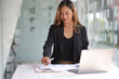 © Wasan - Businesswoman or secretary is working on a financial document using a calculator in the office.