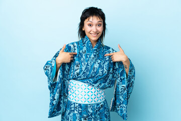 Wall Mural - Young woman wearing kimono over isolated blue background pointing to oneself