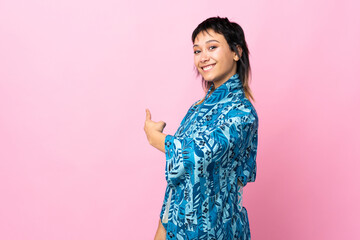 Wall Mural - Young woman wearing kimono over isolated blue background pointing back